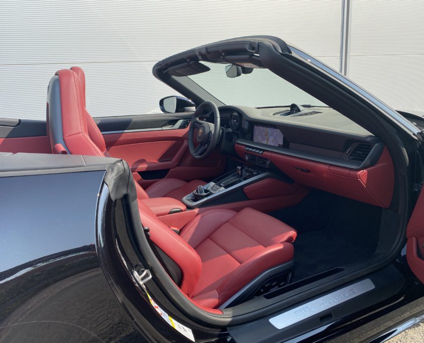 Luxurious red leather interior of high-end convertible Porsche 992 Cabriolet.